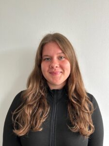 Person mit langen Haaren vor weißer Wand